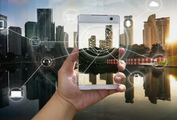 Hand holding a smartphone with a city skyline and glowing connectivity graphics overlaying the scene at sunset/dusk.